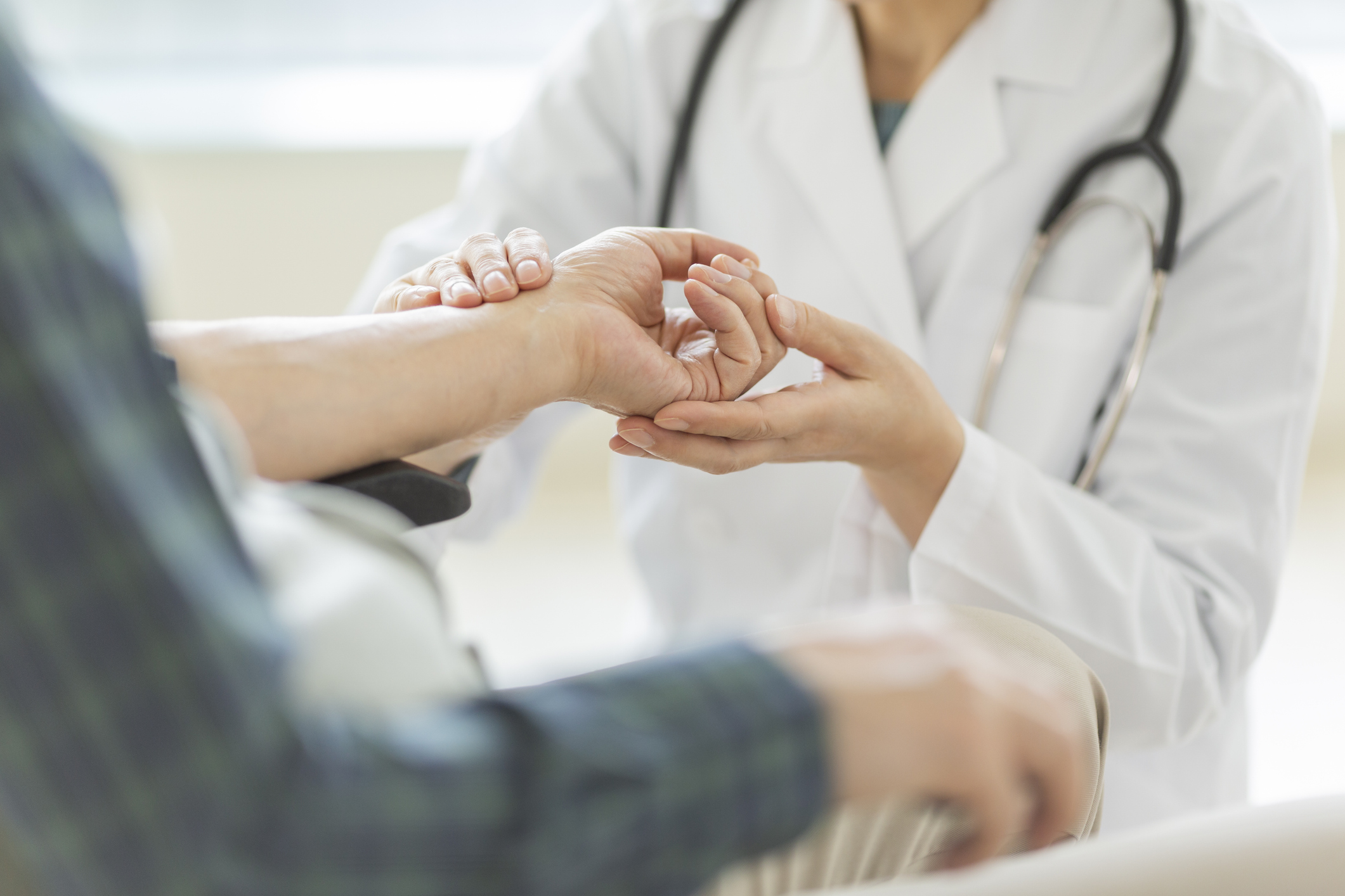 Eine Ärztin hört die Lunge eines älteren Patienten mit einem Stethoskop ab.